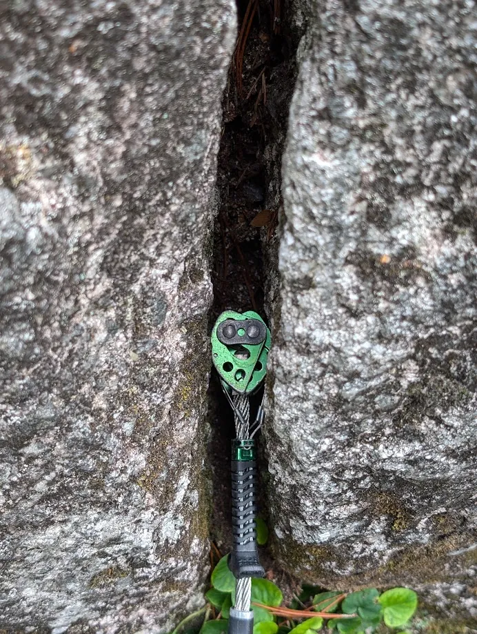 A green cam slotted deep in a narrow granite crack.